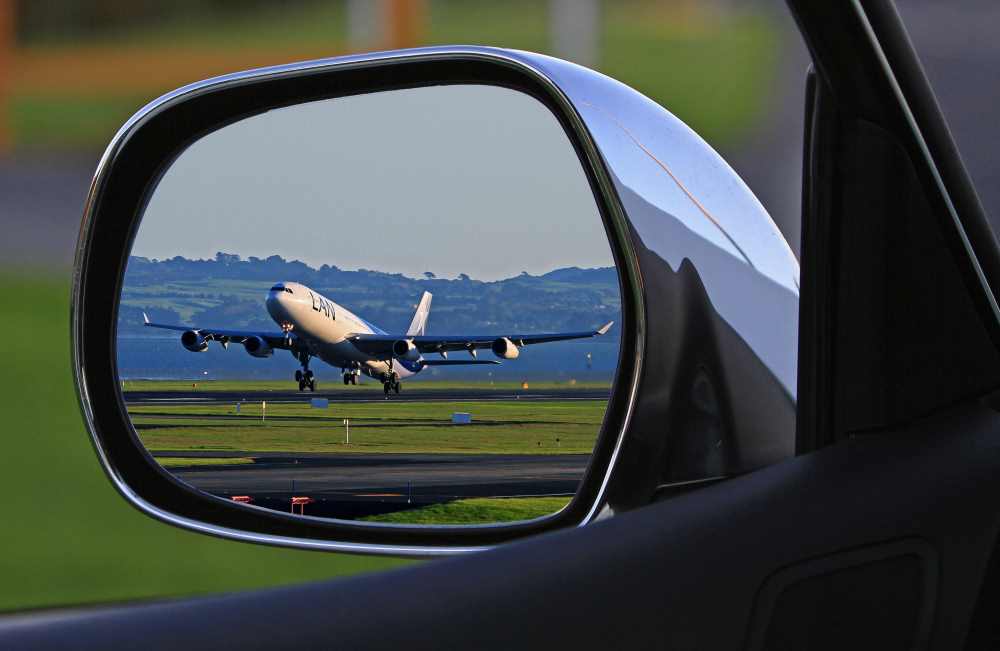 Airport Transfer Service airplane in wing mirror of luxury chauffeur driven car
